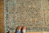 Vintage Sarouk rug: peach field with scrolling charcoal, sky blue floral motifs, dark border.