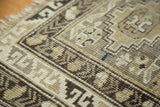 Geometric stepped diamond and serpent border on vintage Caucasian rug with neutral tones, showing even wear.