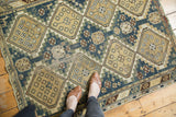Fragmented Caucasian rug showing dusty teal and beige diamond panel motifs with wear.