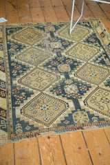Vintage Caucasian rug's repeating diamond panels with floral motifs on a dusty teal field, showing wear.