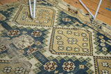 Detail of hand-knotted vintage Caucasian rug, featuring dusty teal, beige geometric patterns, and wear.