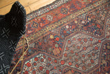 Qashqai carpet showcasing interconnected medallions, pomegranate red, indigo blue, and gold botanical motifs.