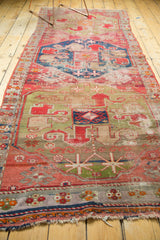 Antique Caucasian runner's tattered end, featuring geometric border motifs in cochineal red and blue.
