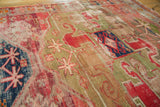 Antique Caucasian rug detail: cochineal red and brilliant green geometric motifs with visible storied wear.