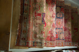 Row of rolled antique hand knotted runners with aged texture, fringed ends, and rich colors.