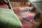 Antique Caucasian rug runner detail with cochineal red, navy cloud bands, gem green, and visible wear.