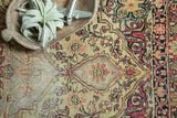 Detailed ivory and cochineal red floral pattern with visible wear on a late 19th century Kermanshah rug.
