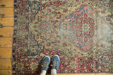 Antique Kermanshah rug: scalloped medallion, ivory, red, and blue patterns, with even pile wear.