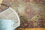 Antique Kermanshah rug featuring cochineal red floral border and aged ivory field patterns.