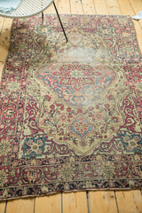 Late 19th-century Kermanshah rug's intricate floral border in cochineal red, ivory, with visible wear.
