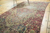 Antique Kermanshah rug border with cochineal red floral motifs and visible pile wear.
