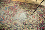 Antique Kermanshah rug detail showing faded red, blue curvilinear motifs and even pile wear.