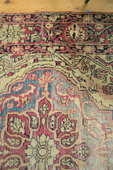 Antique Kermanshah rug detail: cochineal red, ivory, blue floral motifs, with wear to knot heads.
