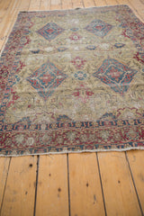 Low angle on a collector's Kermanshah rug showing the detailed border and threadbare ivory field.