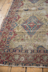 Low-pile texture and threadbare areas on the ivory ground of an antique Kermanshah collector rug.