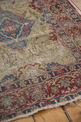 Detailed view of this antique Kermanshah rug showing threadbare pile and tattered sides.