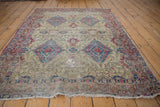 Full perspective of an antique Kermanshah rug, detailing the rare ivory field and its historic wear.