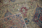 Frayed corner of an antique Kermanshah revealing its hand-knotted foundation and threadbare wear.
