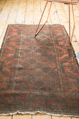 Tattered end of vintage Belouch rug with foundation wear, red rust and charcoal lattice.