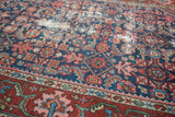 Geometric Herati pattern on navy ground with exposed foundation and brick rust red border.