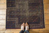 Antique Belouch prayer rug, left edge with indigo, brown geometric border and tattered pile.