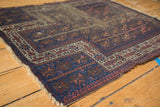 Tattered edge of antique Belouch prayer rug, revealing foundation, indigo, blush, and ivory starburst border.