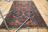 Angled view of the vintage Lilihan rug, showing pale raspberry field and blue teal motifs.