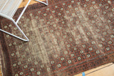 Antique Belouch rug's repeating geometric pomegranate motifs in terra cotta, charcoal, and ivory, showing its patina.