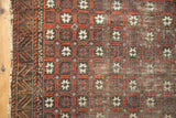 Antique Belouch rug's terra cotta lattice pattern, multi-tone pomegranate motifs, and exposed foundation.