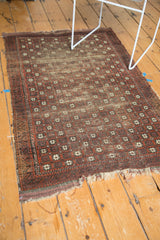 Antique Belouch rug's tattered ends and geometric border in terracotta and dark brown.