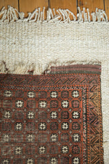 Antique Persian Belouch rug corner detail: tattered fringe, exposed foundation, geometric patterns.