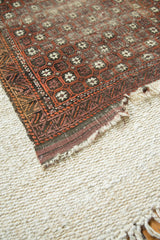 Antique Belouch rug end with hard tatter and geometric motifs in earthy tones.
