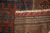 Antique Timuri Belouch rug end with geometric pile, striped kilim, and white securing stitches.