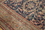 Detail of antique Mahal rug: navy field, coral Mustafi floral design, patterned border.