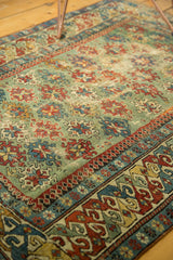 Angled view of an antique Caucasian rug showcasing its rare green field and storied geometric pattern.