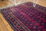 Close-up showing the vintage Belouch rug's violet, navy gul motifs and goat hair selvedge.