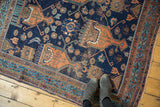 Corner of antique Afshar rug, intricate geometric border, and worn dark indigo field.