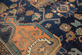 Geometric terra cotta, indigo, and green motifs on an antique Afshar rug showing aged pile.