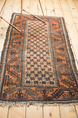 Vintage Belouch rug right side, rust and charcoal geometric border, ivory starburst field.