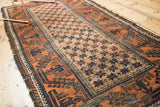 Vintage Belouch rug close-up: ivory lattice starbursts, pale rust border, etched charcoal motifs.