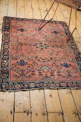 Tattered bottom edge of a vintage Sarouk rug, with floral motifs and navy border.