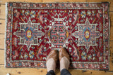 Vintage Karaja rug close-up: central medallion with hook and latch motifs in red, blue, and blush.