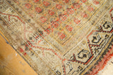 Worn corner of vintage Mir Arak rug with exposed foundation, saffron germinating flower pattern, and tattered edge.