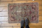 Antique Kerman rug's intricate mil fleur design, cochineal red, blush, navy, and visible foundation wear.