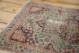 Antique Kerman rug's intricate cochineal red mil fleur design with visible foundation.
