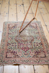 Antique Kerman's worn lower end, featuring tattered fringe and intricate pattern.