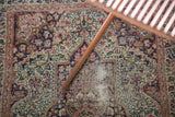 Antique Kerman rug's ornate mil fleur pattern in cochineal red, navy, with visible foundation.