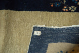 Vintage Peking runner's folded corner reveals beige pile, dark blue border, and hand-knotted weave.