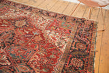 Vintage Heriz rug's dark navy border with geometric motifs and worn cherry red field.