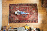 Vintage Heriz carpet, full view with person, showcasing red and navy geometric florals.